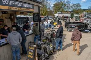 Equipment rental yard staff managing fleet bookings on a busy Saturday morning